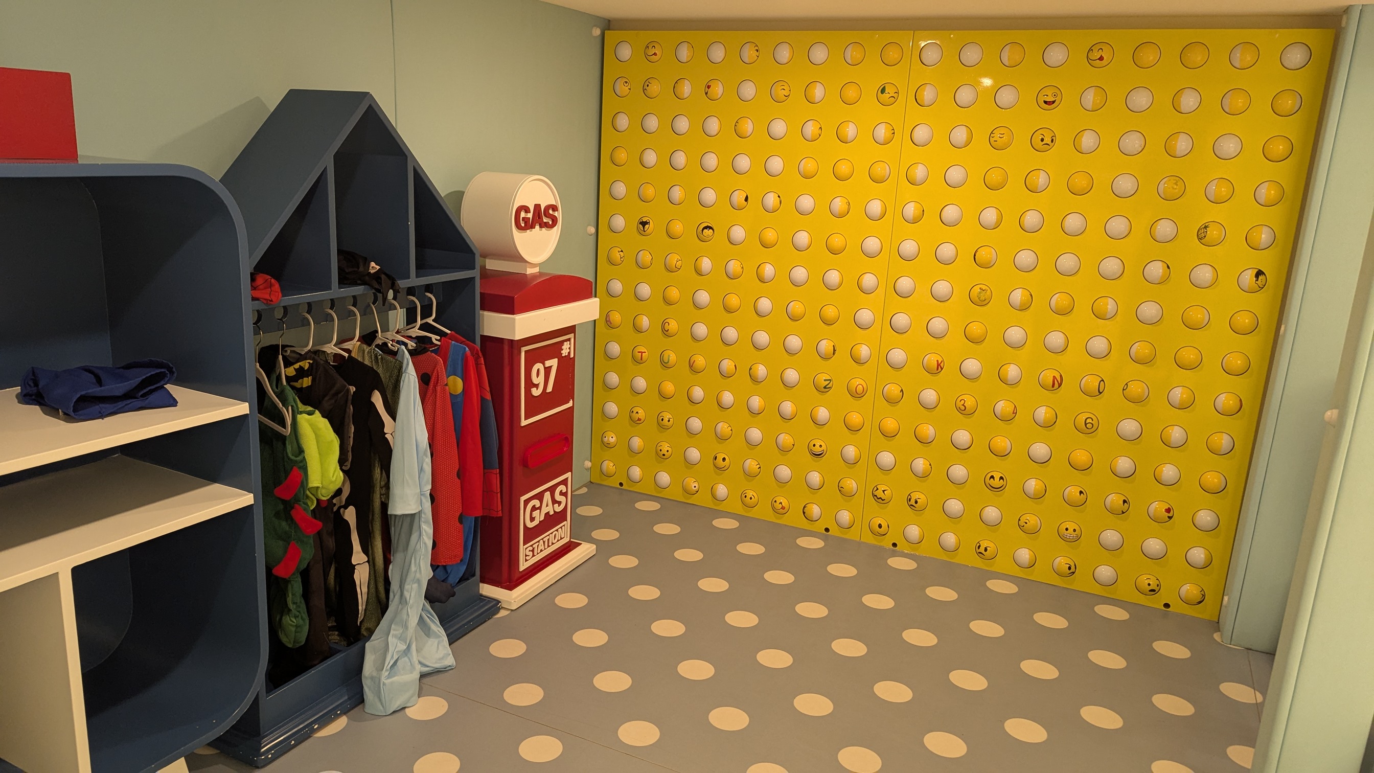 A dress up station with a collection of costumes including superheroes and a dinosaur.