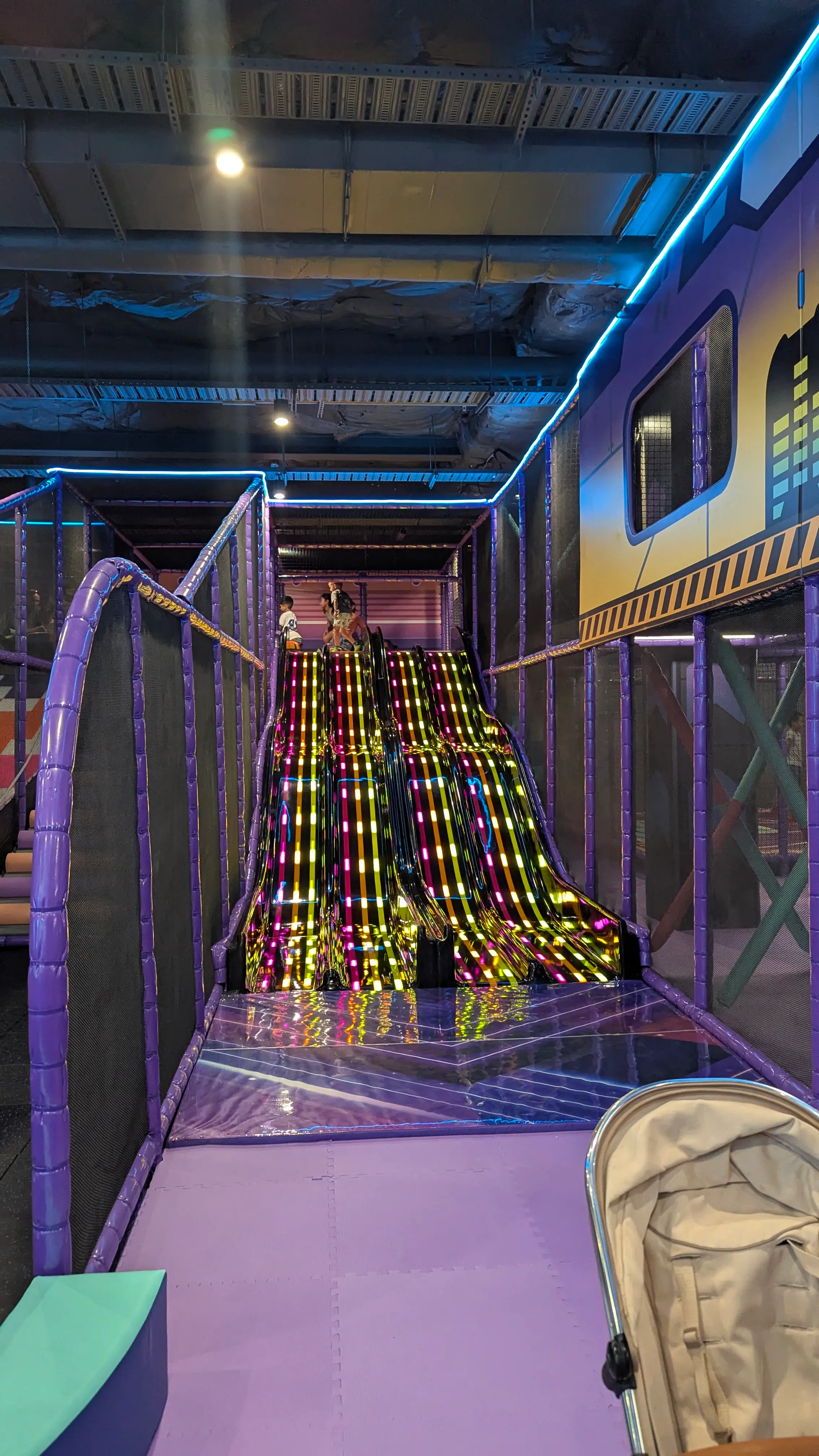 Wide, multi-lane racing slide with bright LED light strips and soft padded landing area.