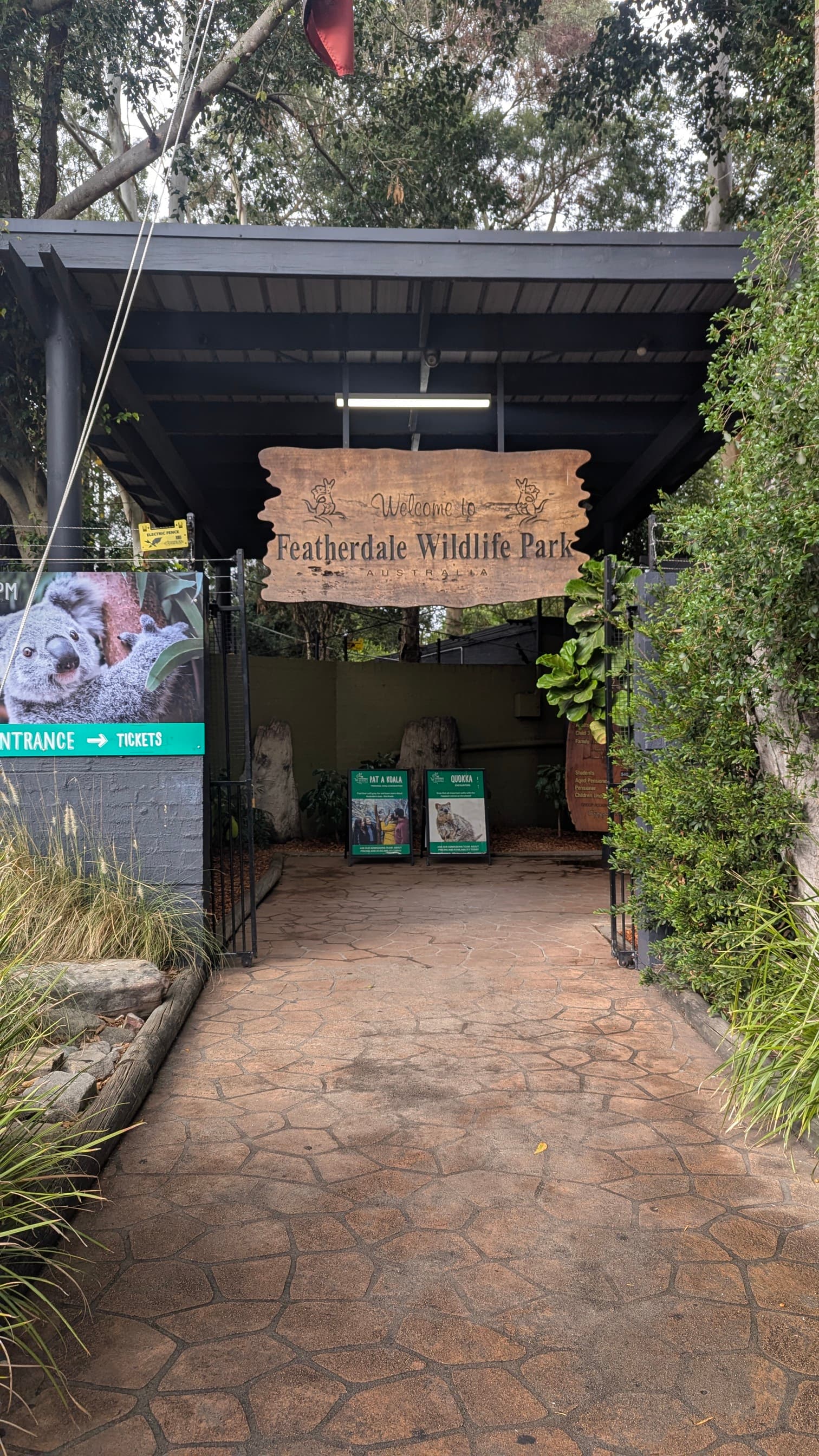 Main entrance to Featherdale Wildlife Park with a rustic wooden "Welcome to Featherdale Wildlife Park" sign.