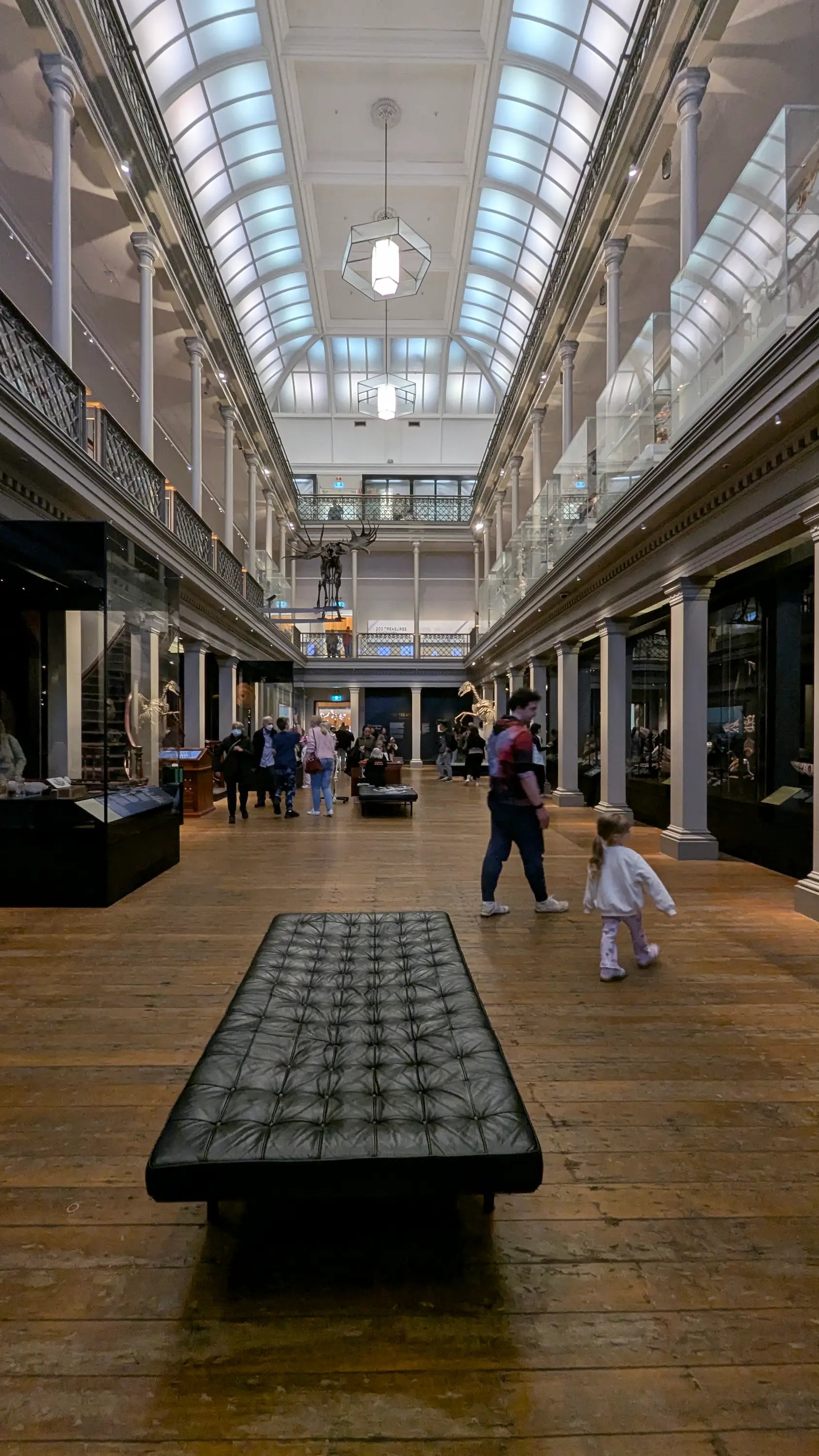 Grand, multi-level museum gallery with high glass ceilings, wooden floors, and wide paths suitable for strollers.