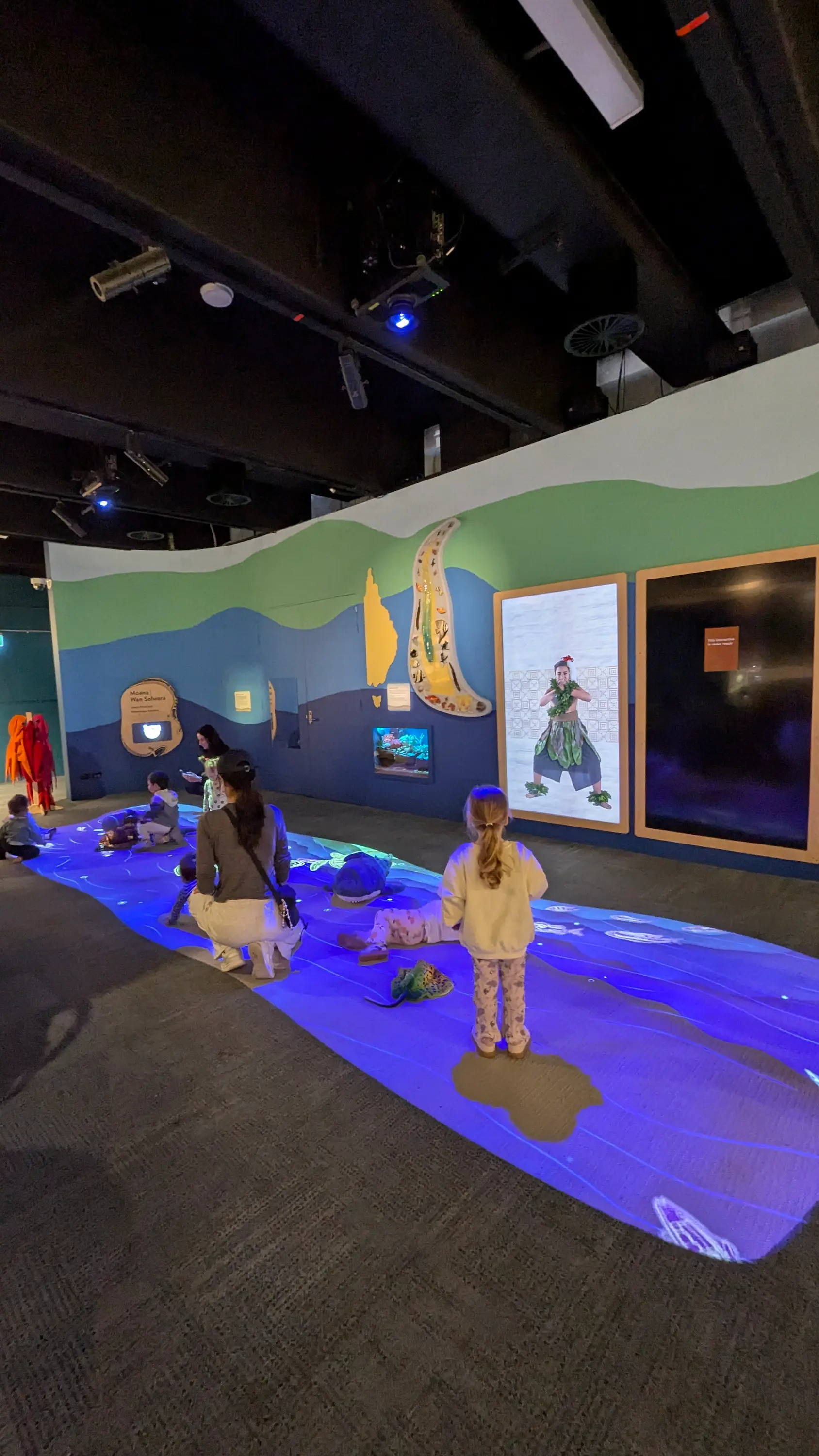 Interactive "Burra" learning space with an illuminated blue floor projection and educational wall murals.