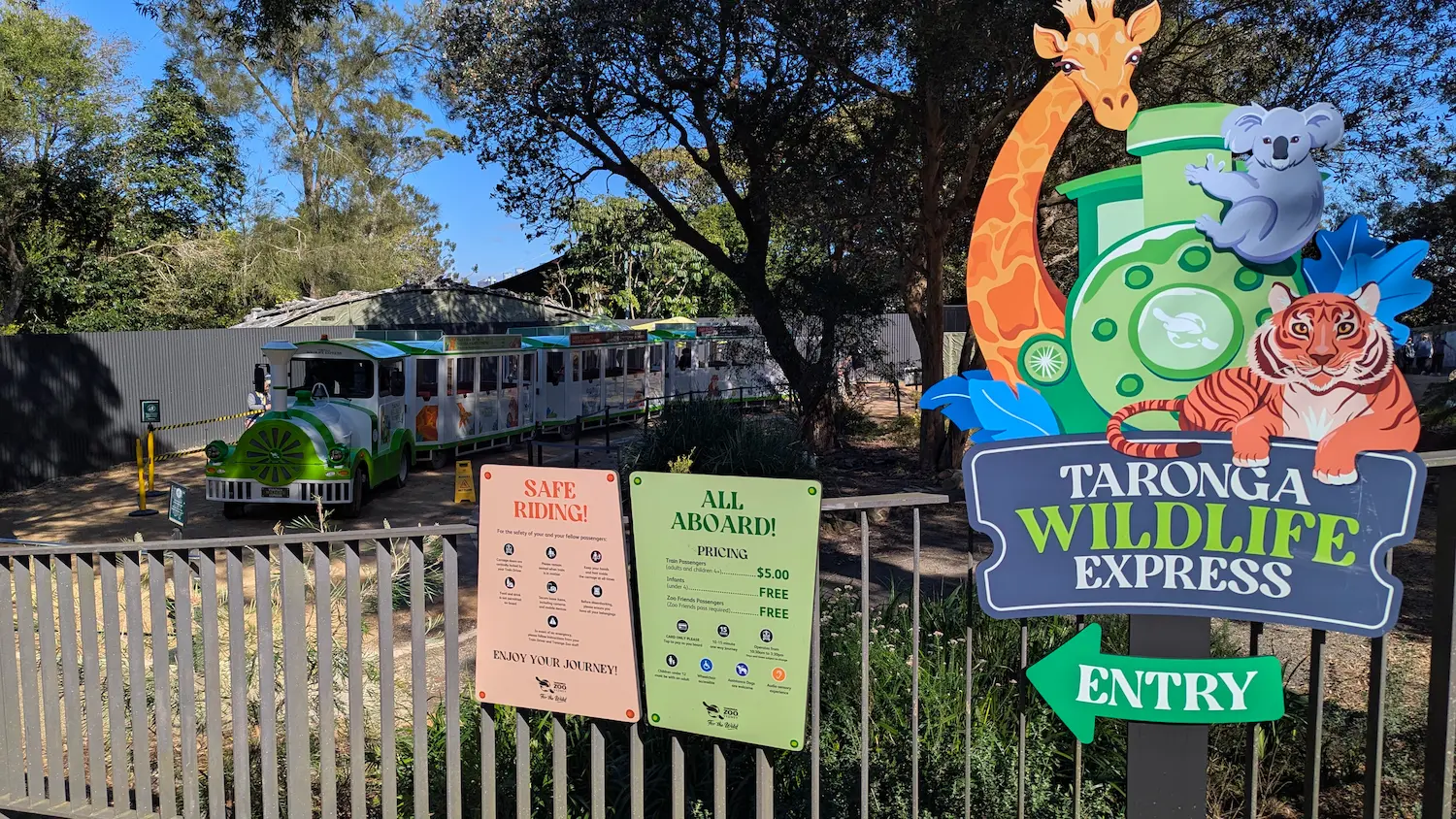 The entry to a green and white trackless train with clear signage for pricing, safety rules, and an accessible boarding area.