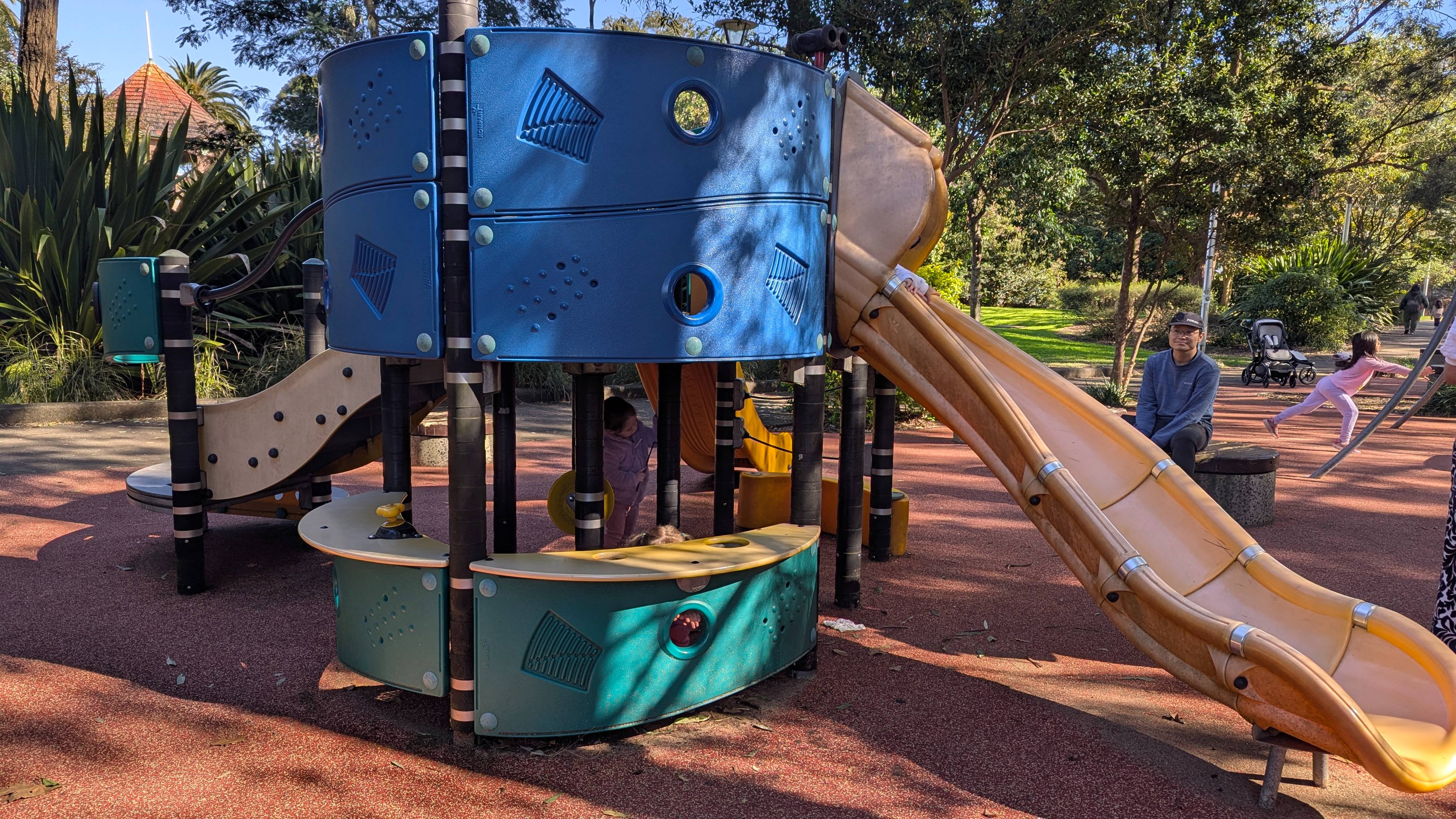 Colourful outdoor playground with slides, swings and climbing structure.