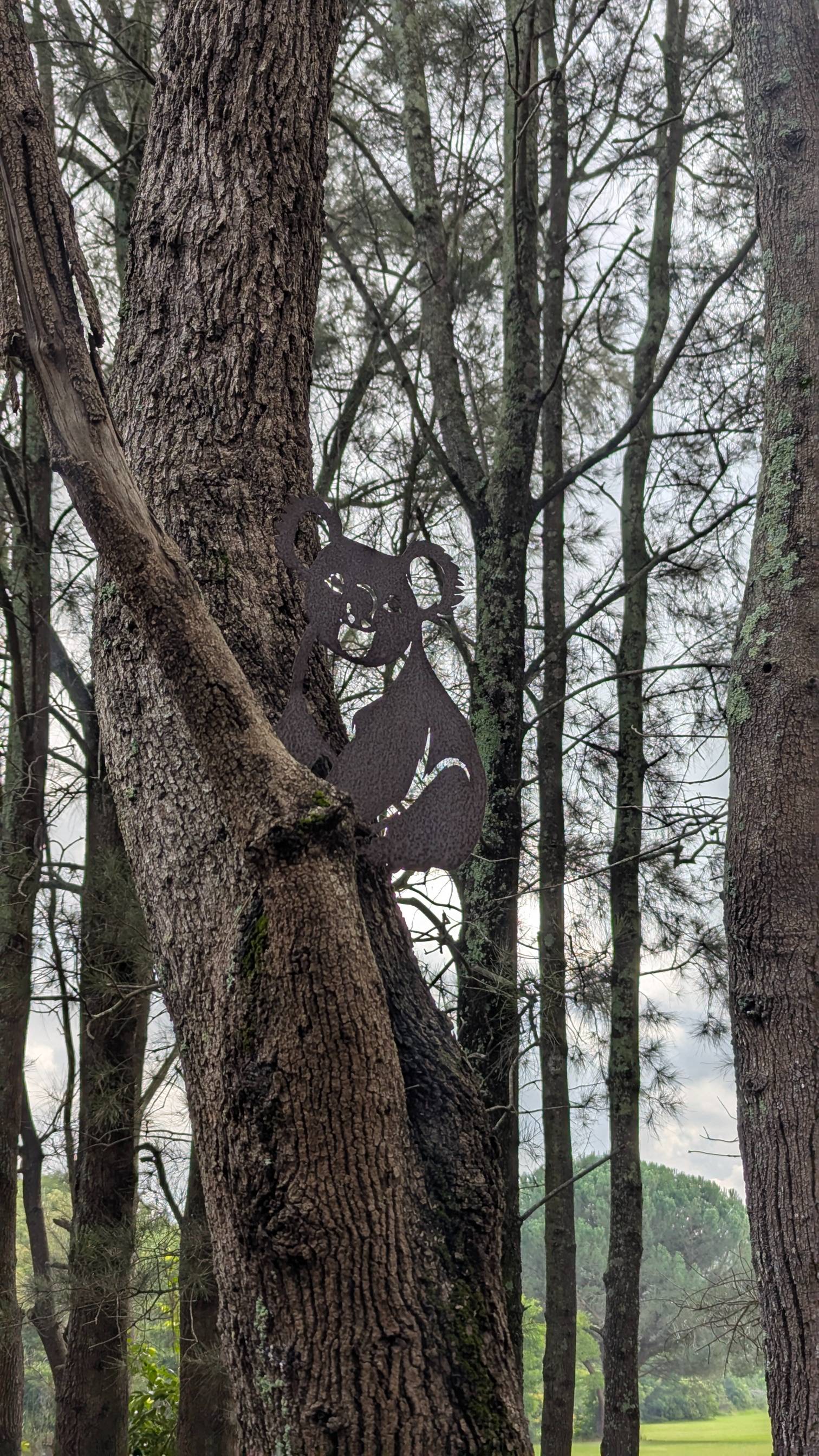Metal koala attached to a tree.