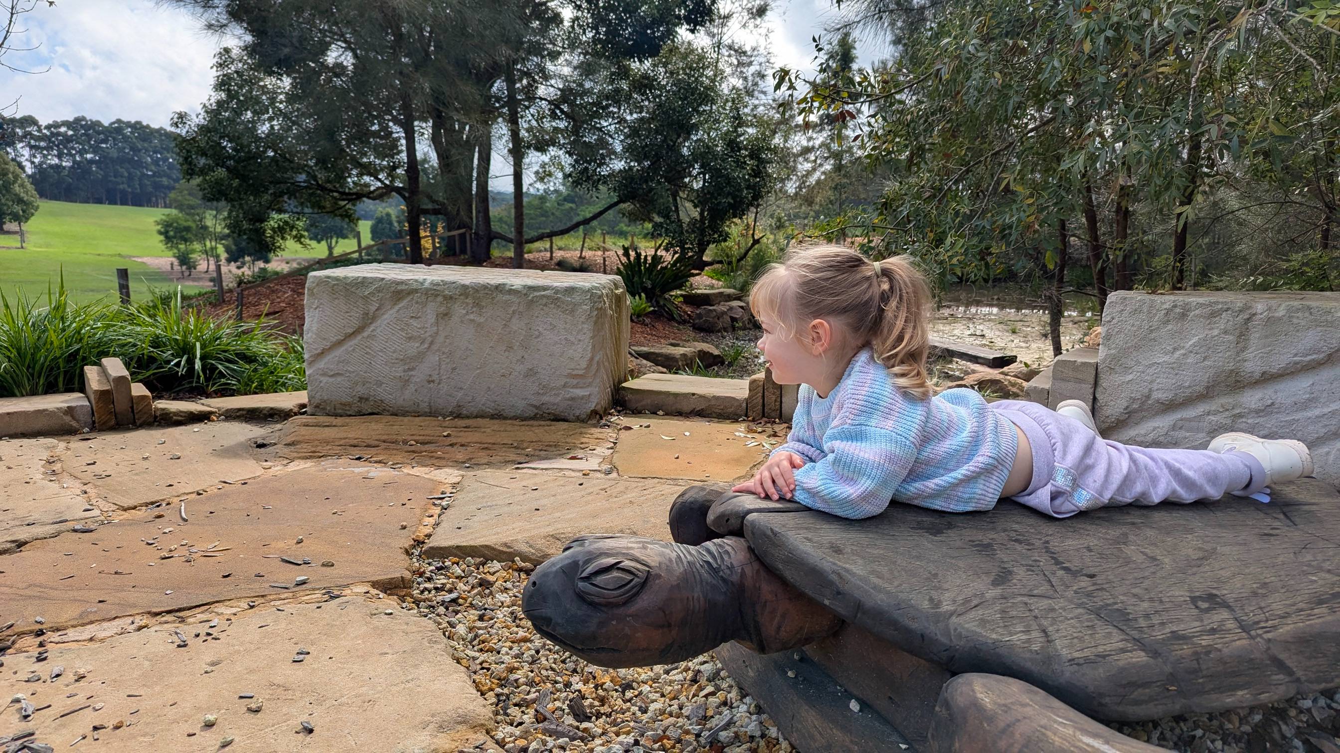 Large wooden turtle on a stone platform overlooking the pond.