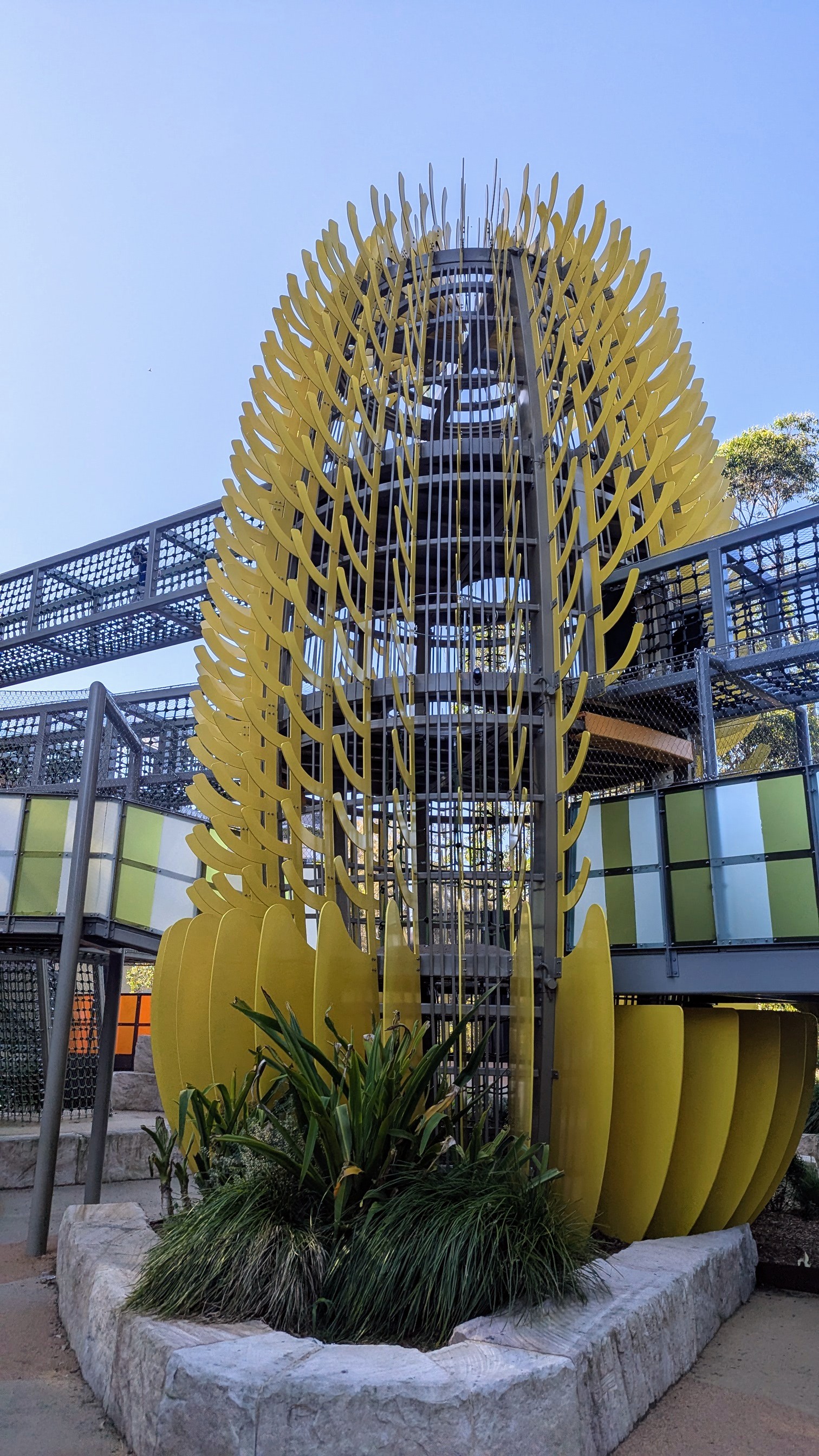 Modern multi-level playground with climbing nets and bridges.
