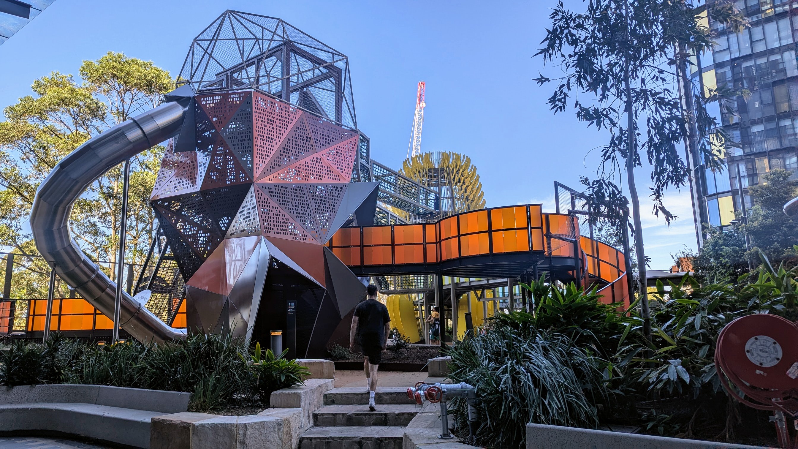 Colourful modern playground with a spiral slide, surrounded by greenery.
