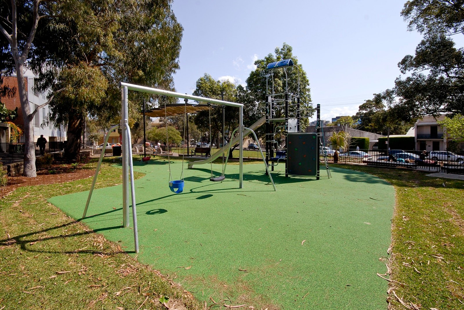 Playground at Charles Kernan Reserve with swings, slide, and climbing structure on green softfall.
