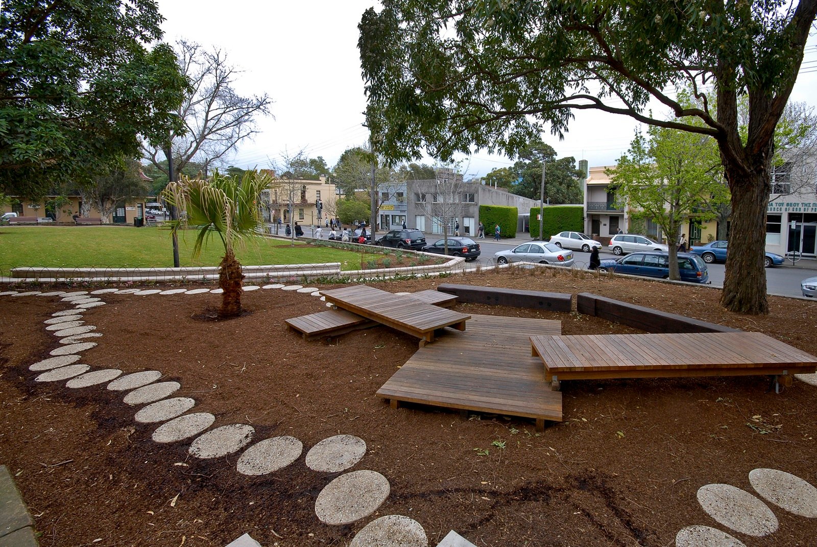 Landscaped area at Charles Kernan Reserve with wooden platforms, stepping stones, and surrounding trees.