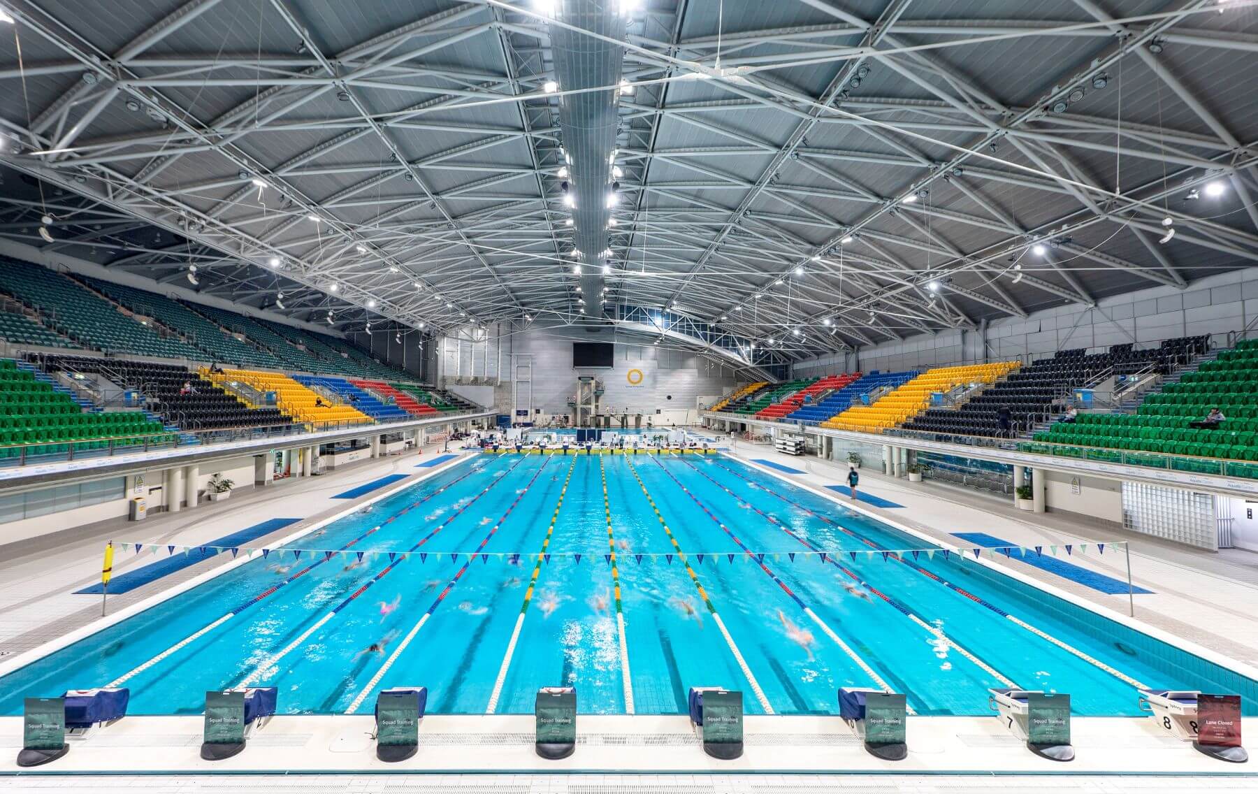 10 lane indoor pool surrounded by stadium seating.
