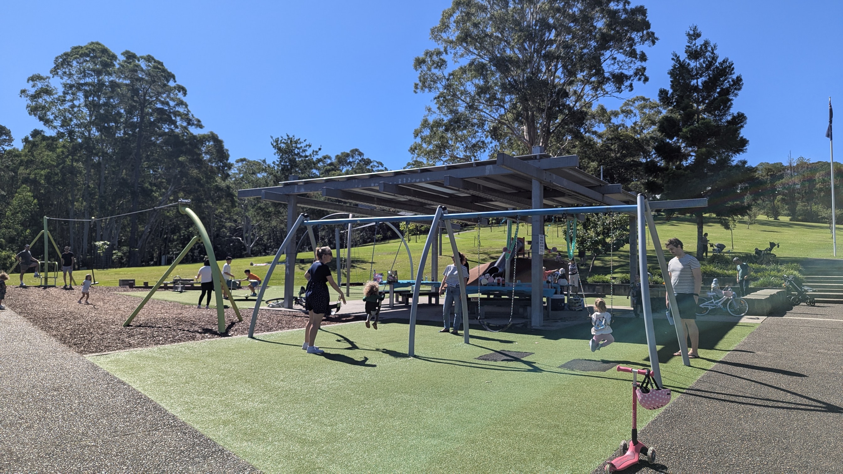 Outdoor playground with swings, a flying fox and slide in the background.