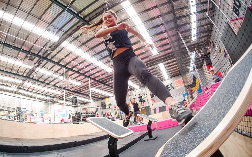 A jumper performing a trick over a trampoline in the main free-jump arena at BOUNCE Homebush.