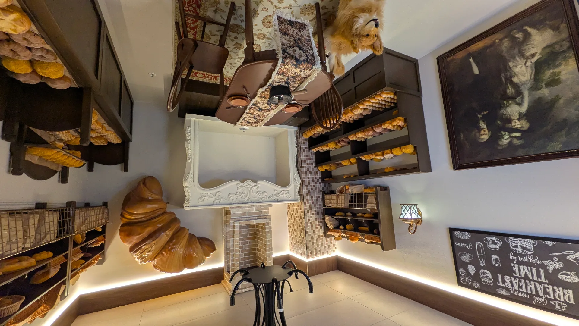Upside-down view of a cozy bakery interior with wooden shelving displaying fresh bread loaves, wicker baskets, decorative ceiling beams, and warm lighting creating an inviting atmosphere.