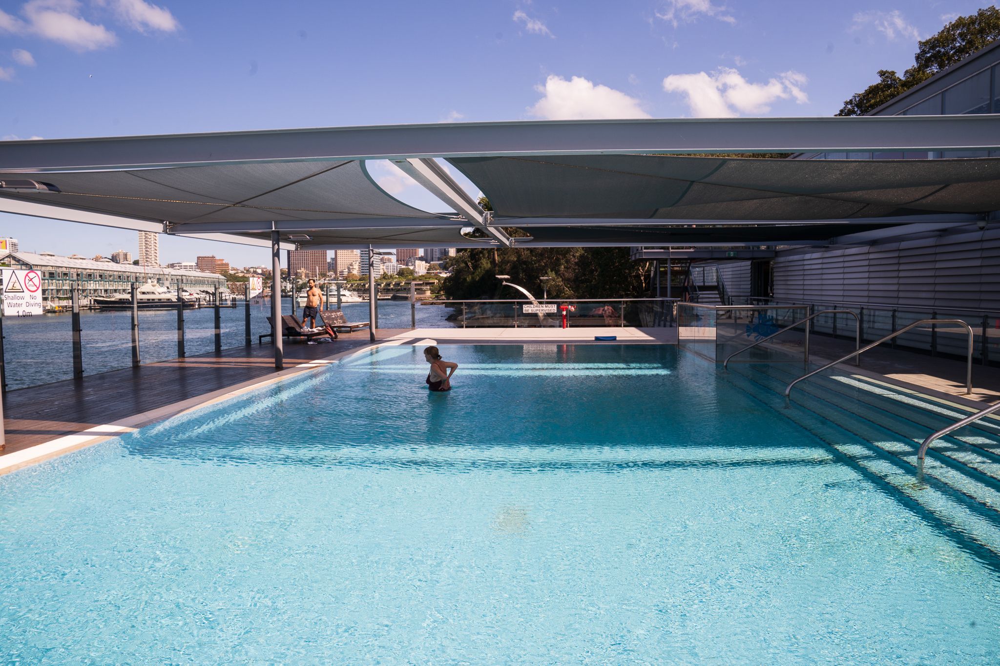 Poolside sun lounges and shaded seating beside the pool at Andrew (Boy) Charlton Pool, Sydney.